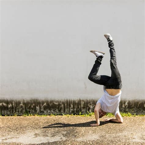Free Photo Young Male Dancer Doing Handstand Against Gray Wall