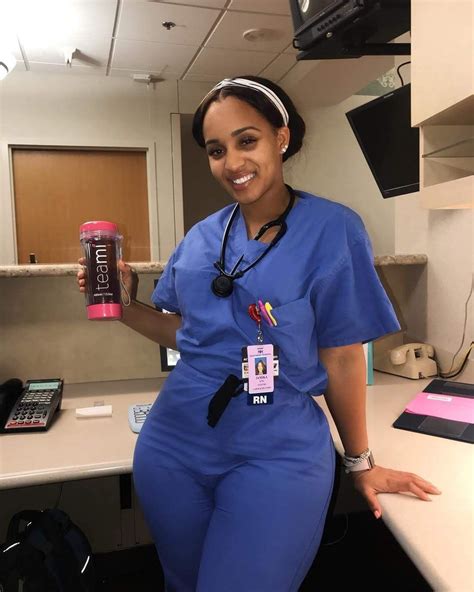 A Woman In Scrubs Is Holding Up A Can