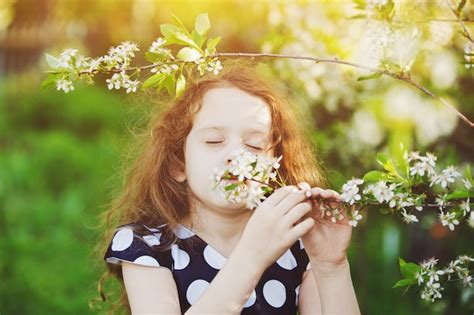 El niño está oliendo la rama de cerezo en flor Foto Premium