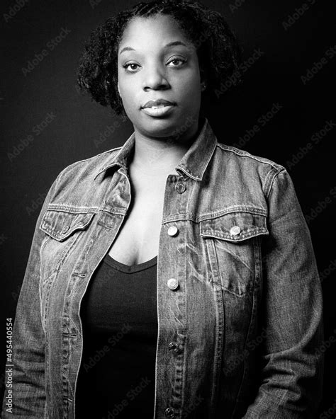 Grayscale Portrait Of Mature Black Woman In Denim Jacket Against Dark