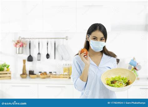 Young Woman Cooking Delicious Food In The Kitchen And Wearing Face