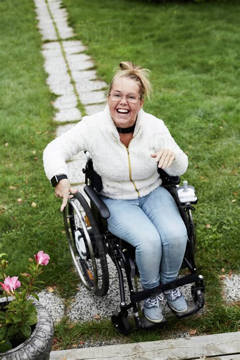Full Length Portrait Of Smiling Disabled Woman Sitting On Wheelchair In