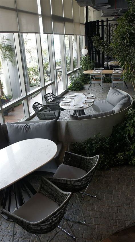 An Indoor Seating Area With Tables Chairs And Plants On The Wall Next