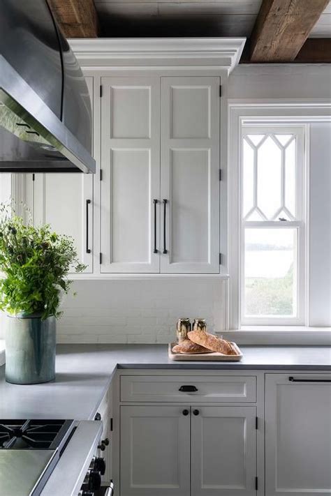You don't see that every day. White kitchen cabinets contrasted with oil rubbed bronze pulls are mounted over a white brick ...