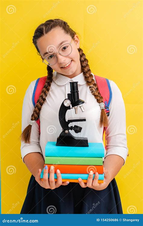 Portrait Of A Schoolgirl In Glasses With Books Textbooks On A Yellow