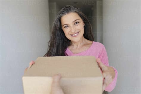 Beautiful Smiling Woman Receiving Package From Delivery Person Stock Photo