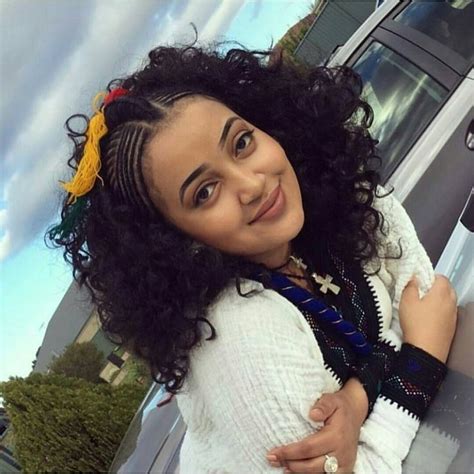 A Woman With Curly Hair Wearing A White Sweater And Scarf Posing For A Selfie