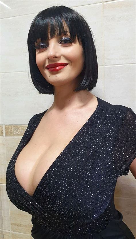 A Woman With Short Black Hair And Red Lipstick Posing In Front Of A