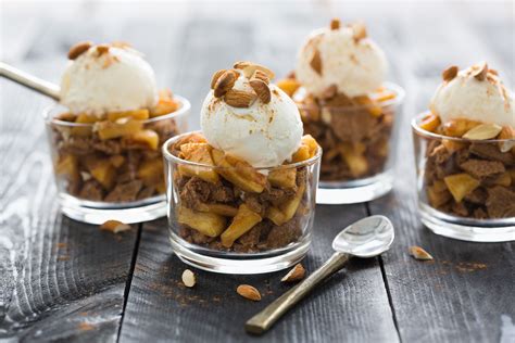 Four desserts with ice cream and nuts in glass dishes on a wooden