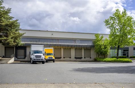 Small Rigs Semi Trucks With Box Trailers Standing In Warehouse Dock For