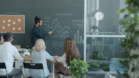 Ambitious Arab Man Making Presentation With Chalkboard While Colleagues