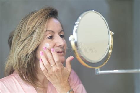 Senior White Woman Applying Moisturizer For Skin Care On Her Face