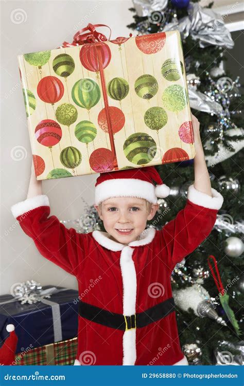 Boy In Santa Claus Outfit Carrying Present On Head Stock Photo Image