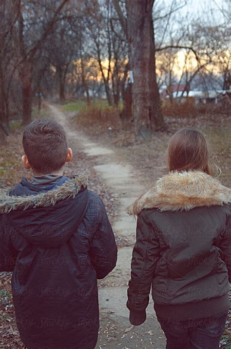 Boy And Girl Walking Through The Woods Near The River In Sunset By