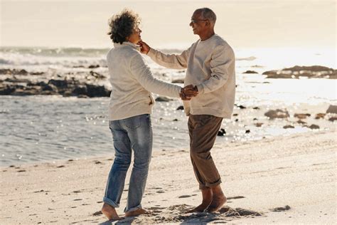 Happy Elderly Couple Smiling And Dancing Together On Beach Sand Mature