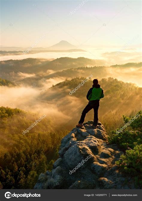 Man On Top Of Mountain Hiker Climbed On Peak Of Rock Above Foggy