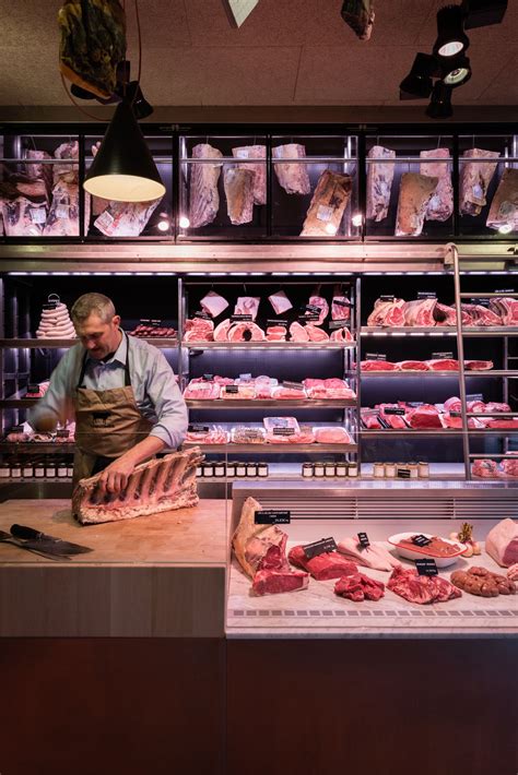 A Man Standing In Front Of A Butcher Shop Counter With Raw Meat On
