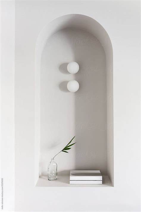 A White Wall With Three Lights And A Vase On The Shelf Next To It By An