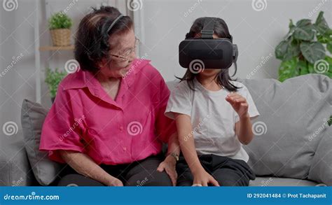 Smiling Overjoyed Mature Grandmother With Little Granddaughter Using Vr On Cozy Couch Happy