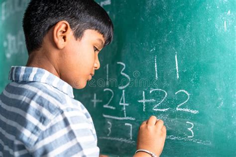 Intelligent Elementary School Kid Solving Maths Problem On Chalkboard