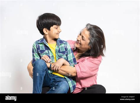 Happy Indian Grandmother And Grandson Hug Sit On Floor Look At Each Other Smiling Isolated On