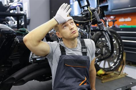 Tired Male Repairman Holding His Head Near Motorcycle Stock Photo