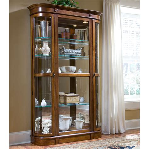 This traditional style cabinet is made of wood and finished in a chestnut stain. Pulaski Pecan Curio Display Cabinet at Hayneedle