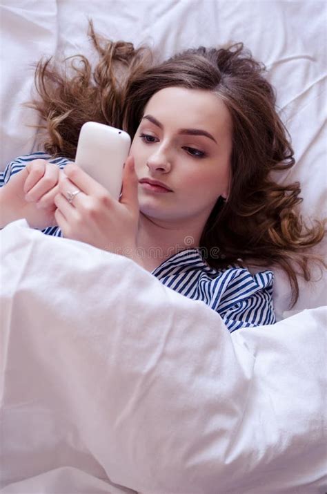 Closeup Of Pretty Teenage Girl Lying In Bed An Looking At Her Mobile Phone Stock Image Image