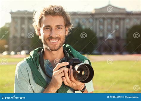 Young Male Photographer Holding Professional Camera On Street Stock