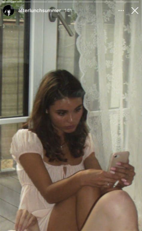 A Woman Sitting On The Floor Looking At Her Cell Phone While Shes