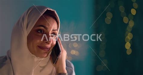 سيدة عربية في المنزل ، تقوم بإجراء مكالمة هاتفية بإستخدام الهاتف المحمول، العمل عن بعد، مفهوم