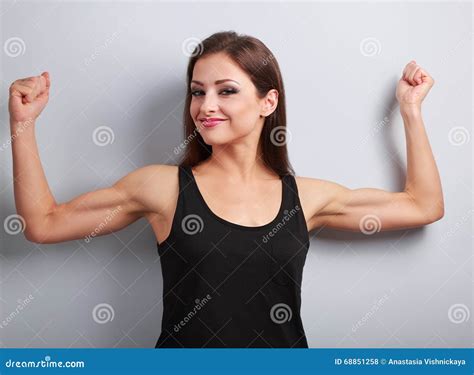 Pleased Strong Young Woman Showing Muscle Biceps With Smiling On Stock
