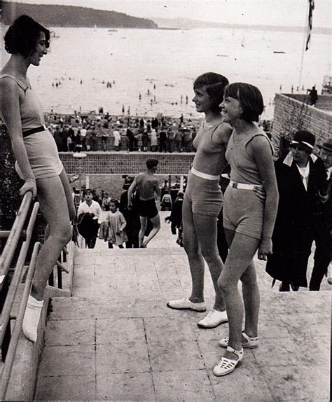 Three Women In Bathing Suits Are Standing On The Edge Of A Pier And