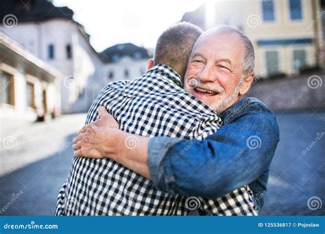 Father And Son Hugging While Smiling At Each Other Standing In Green