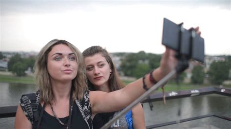 Two Young Beautiful Girls Take Selfie Photo By Mobile Phone And Stick