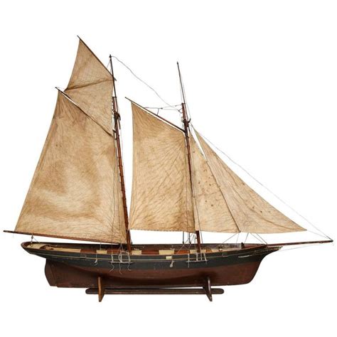 A Wooden Model Sailboat With White Sails And Brown Sails On An Isolated