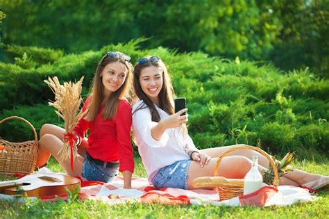 Premium Photo Two Young Beautiful Girls Having Fun On The Picnic Making Selfie On A
