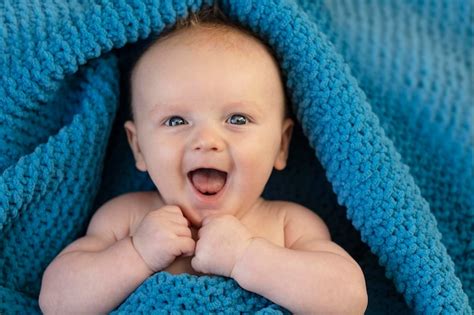 Premium Photo A Happy Laughing Baby Wrapped In A Cosy Bllue Blanket