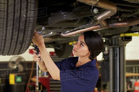 Female Auto Mechanic Working Underneath Car In Garage Stock Photo Dissolve