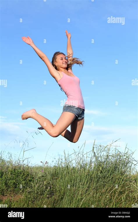 Blonde Teenager Girl Jumping Happy In The Mountain With The Blue Sky In