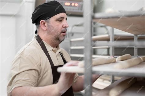 Premium Photo Baker Placing Tray With Formed Raw Dough On Rack Trolley Ready To Bake In The Oven