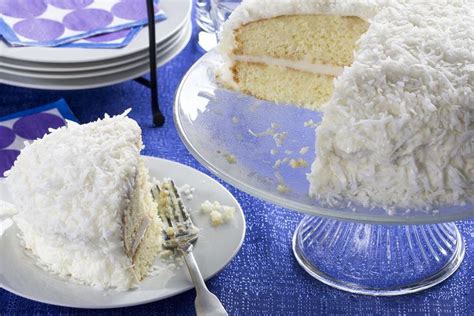 A Cake With White Frosting Sitting On Top Of A Table Next To Plates And