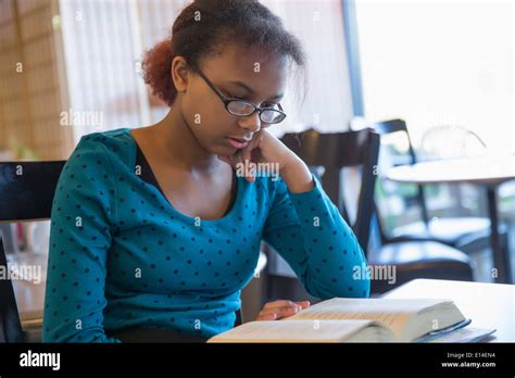 Mixed Race Girl Reading Book In Cafe Stock Photo Alamy