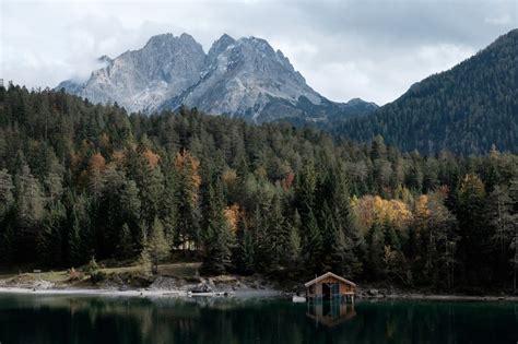 A Boathouse On A Quiet Lake With Imposing Mountains On The Horizon