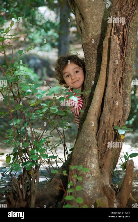 Young Boy Hiding Behind A Tree In The Forest Stock Photo Alamy