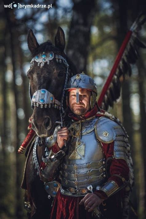 A Man In Armor Standing Next To A Horse