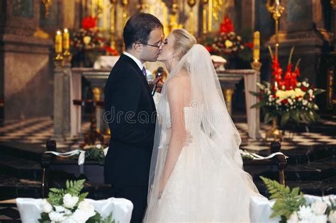 Newlywed Bride And Groom First Kiss At Wedding Ceremony In Church Stock