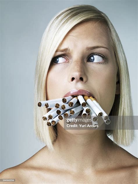 Studio Portrait Of Young Woman With Mouthful Of Cigarettes High Res