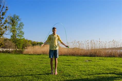 Young Caucasian Boy Is Doing Workout With Jumping Rope On Green Grass