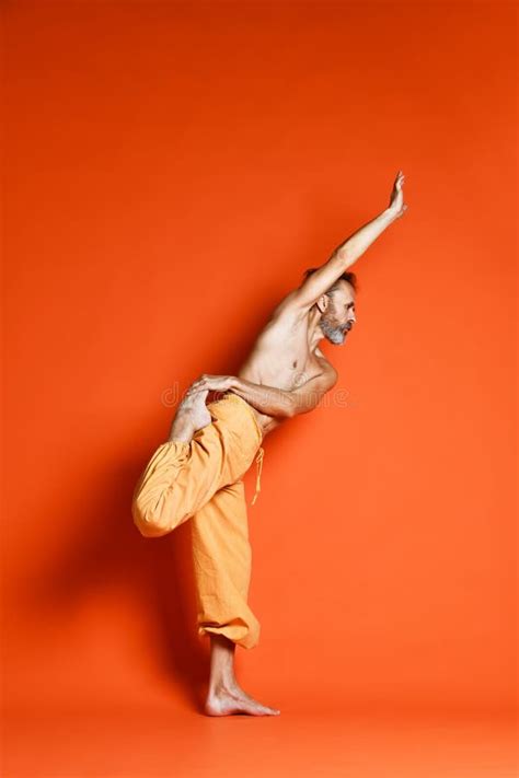 Old Man Practicing Yoga Doing Stretching Exercises Against Orange